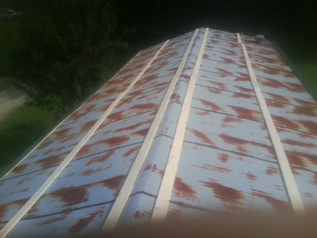 Rusted metal roof panels with new wood purlins before replacement — Storm Damage Roof Repair in New Woodstock by Roofing Brothers