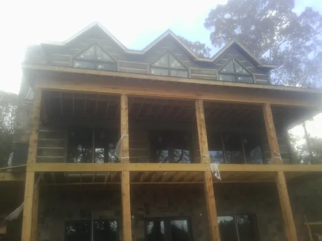 Dormers and porch framing on a large log home under construction — Roof Coating work by our crew in New Woodstock