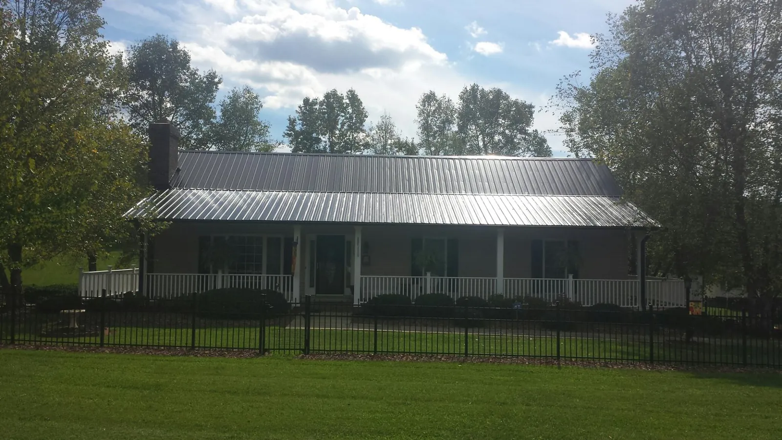 Gray metal roof on a brick ranch with a full width front porch — Gutter Guard Installation work by our crew in New Woodstock