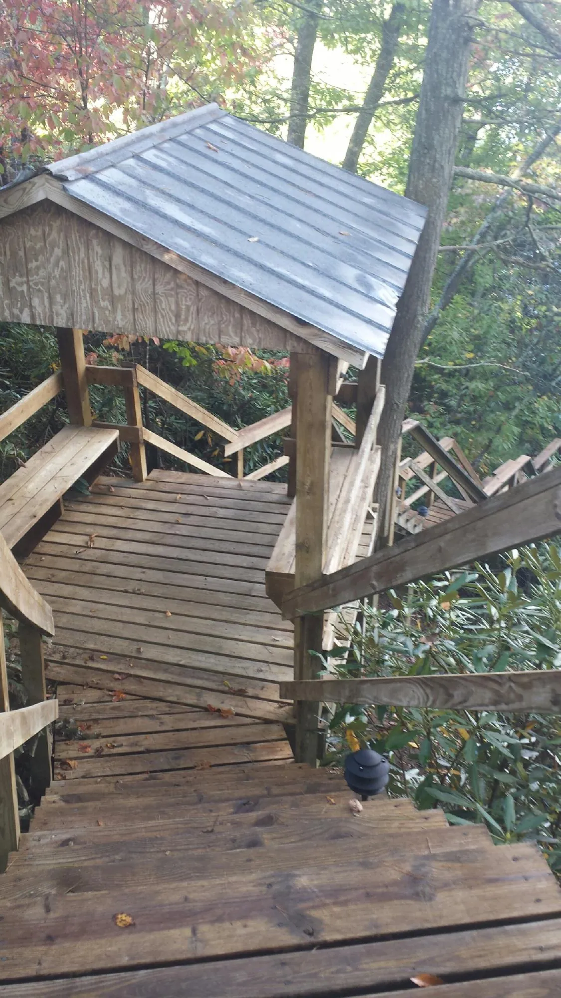 Metal roofed shelter over wooden steps on a wooded walkway — Skylight Repair & Installation work by our crew in New Woodstock