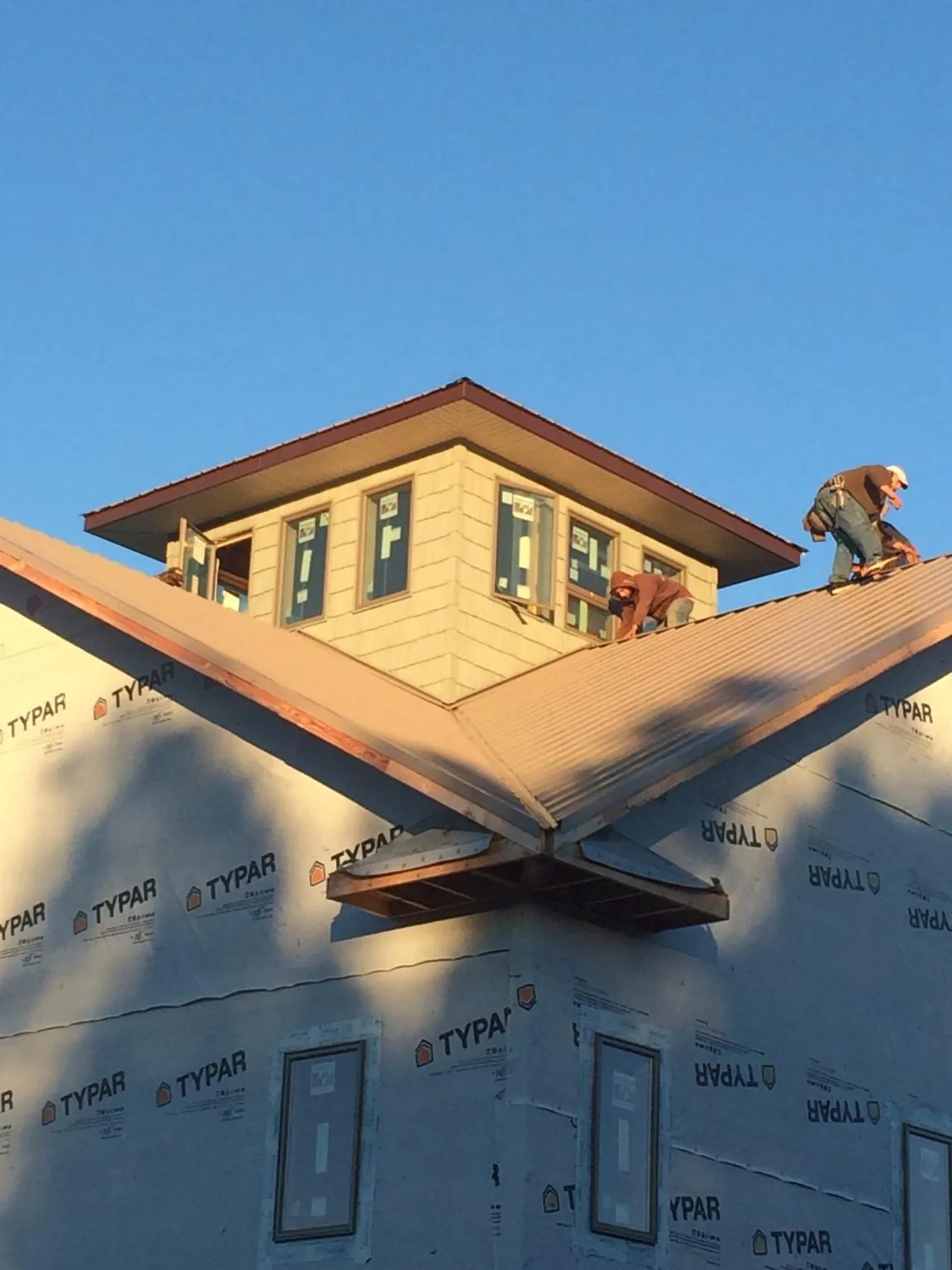Roofers working around a rooftop cupola on a new metal roof at sunset — Roof Waterproofing in New Woodstock by Roofing Brothers